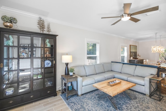 living room featuring ceiling fan with notable chandelier and crown molding