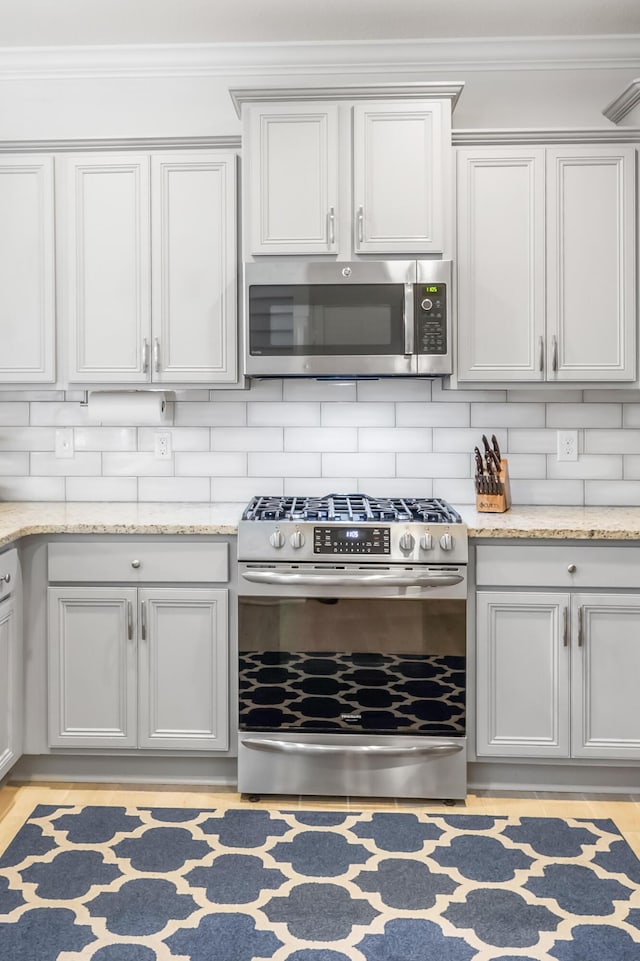 kitchen with light stone counters, appliances with stainless steel finishes, and decorative backsplash