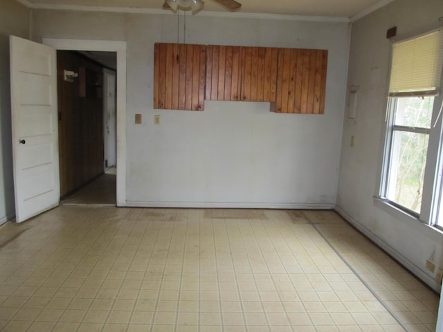 empty room featuring ceiling fan and crown molding