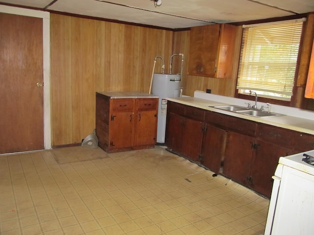 kitchen with water heater, white range with gas cooktop, wood walls, and sink