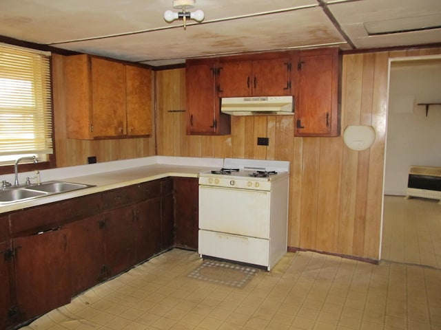 kitchen with sink, white gas stove, heating unit, and wood walls