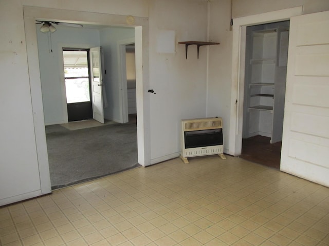 spare room with ceiling fan, heating unit, and light colored carpet