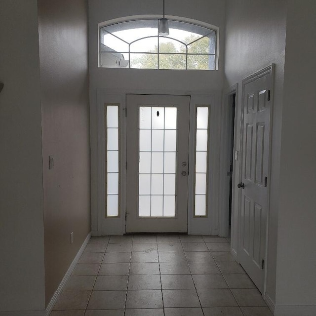 foyer entrance featuring light tile patterned flooring and a towering ceiling