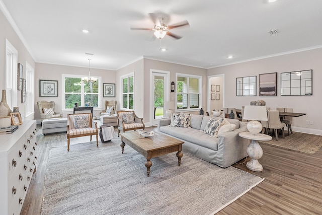 living room with ceiling fan with notable chandelier, ornamental molding, and light hardwood / wood-style floors