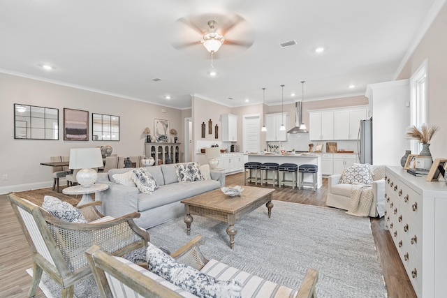 living room with ceiling fan, light hardwood / wood-style flooring, and ornamental molding