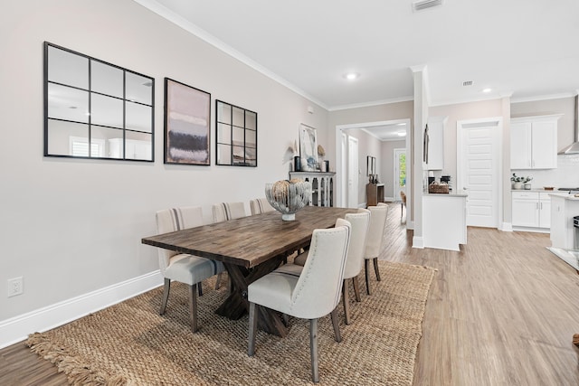 dining room with ornamental molding and light hardwood / wood-style floors