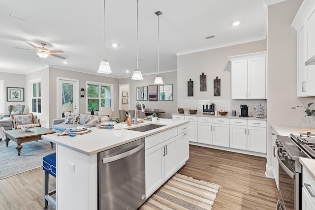 kitchen featuring pendant lighting, appliances with stainless steel finishes, sink, white cabinetry, and a center island with sink