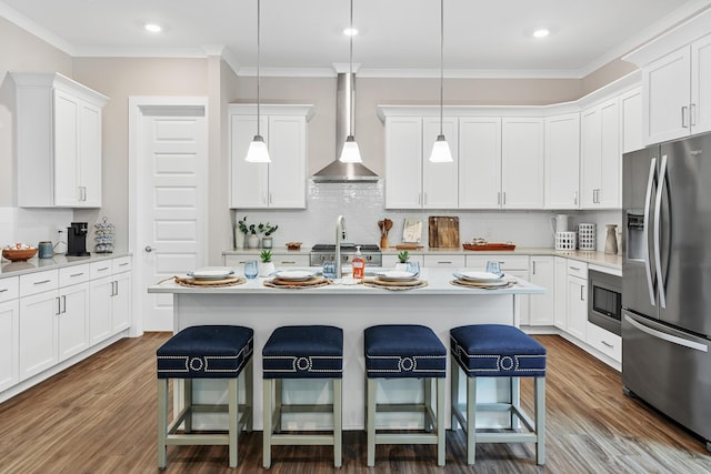 kitchen featuring white cabinets, stainless steel appliances, hanging light fixtures, and a kitchen island with sink