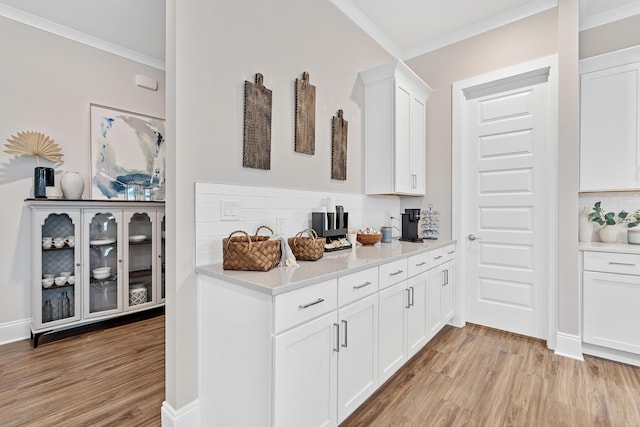 bar featuring backsplash, white cabinetry, light hardwood / wood-style flooring, and crown molding