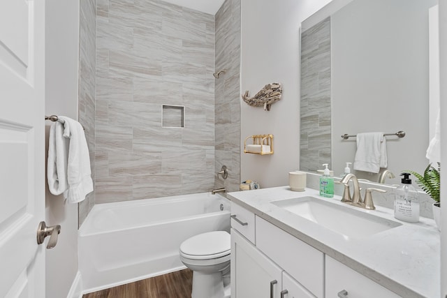 full bathroom with hardwood / wood-style floors, toilet, vanity, and tiled shower / bath combo