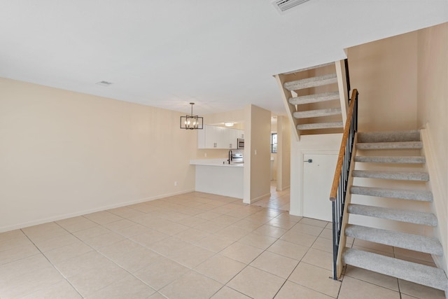 stairway featuring tile patterned floors, a chandelier, and sink