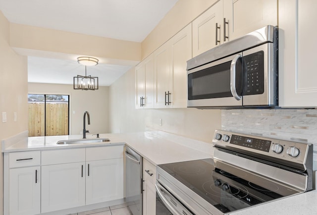 kitchen featuring appliances with stainless steel finishes, pendant lighting, sink, white cabinets, and kitchen peninsula