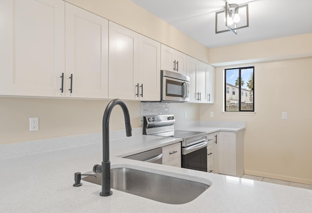 kitchen with stainless steel appliances, white cabinetry, sink, and light tile patterned floors