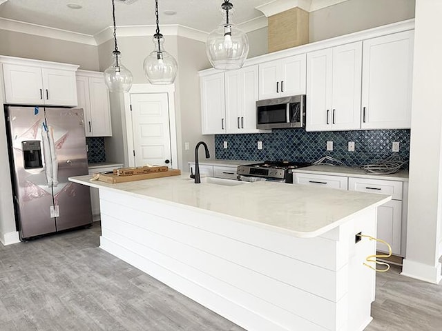 kitchen featuring a kitchen island with sink, sink, decorative light fixtures, and stainless steel appliances