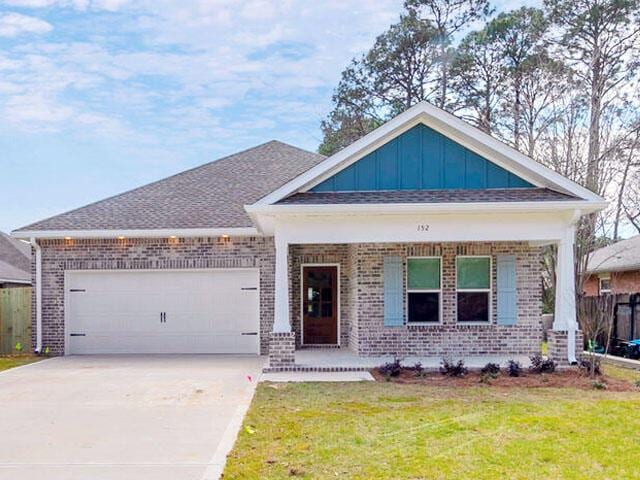 view of front of property featuring a garage, brick siding, driveway, board and batten siding, and a front yard