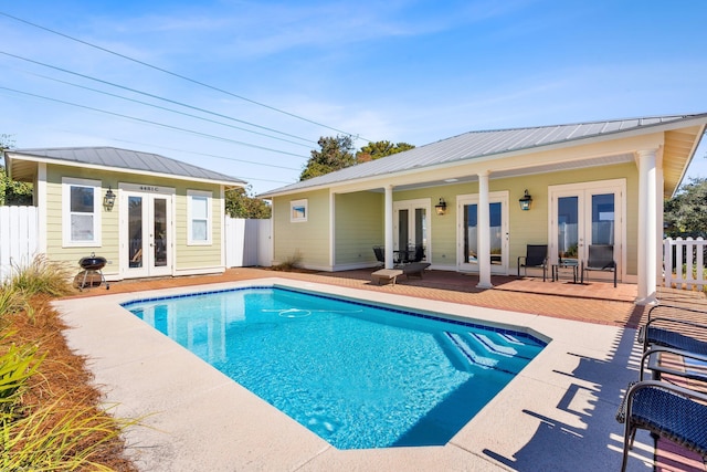 view of pool with french doors, an outdoor structure, and a patio