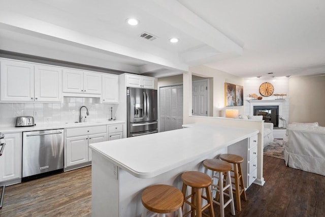 kitchen featuring white cabinetry, appliances with stainless steel finishes, dark wood-type flooring, and a kitchen bar