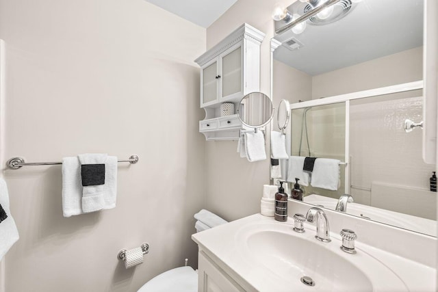 bathroom featuring vanity, toilet, and a shower with shower door