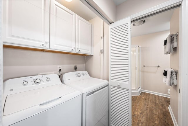 clothes washing area featuring washer and dryer, dark wood-type flooring, and cabinets