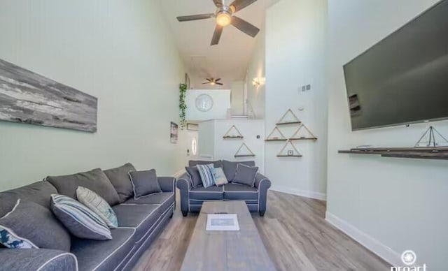 living room featuring hardwood / wood-style floors, a high ceiling, and ceiling fan