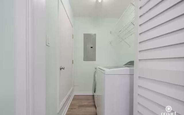 washroom featuring electric panel, light hardwood / wood-style flooring, and washer and clothes dryer