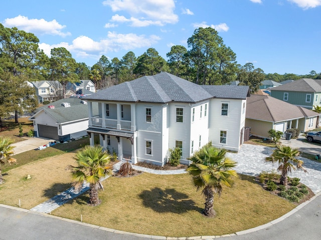 view of front of property with a garage, a balcony, and a front lawn