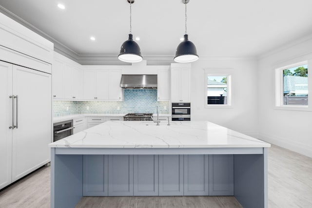 kitchen featuring white cabinetry, light stone counters, oven, a kitchen island with sink, and wall chimney range hood