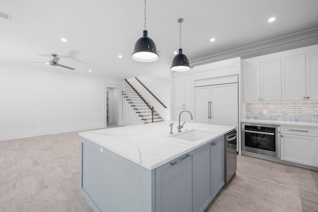 kitchen featuring sink, hanging light fixtures, a center island with sink, stainless steel appliances, and light stone countertops