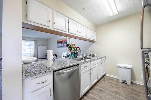 kitchen featuring sink, stainless steel dishwasher, light stone countertops, light hardwood / wood-style floors, and white cabinets