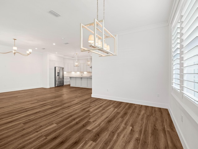 unfurnished living room featuring a notable chandelier, dark wood-type flooring, and ornamental molding