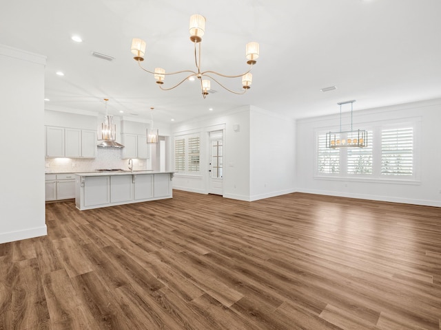 unfurnished living room with a healthy amount of sunlight, ornamental molding, dark hardwood / wood-style floors, and a chandelier