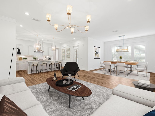 living room featuring ornamental molding, a chandelier, and light wood-type flooring