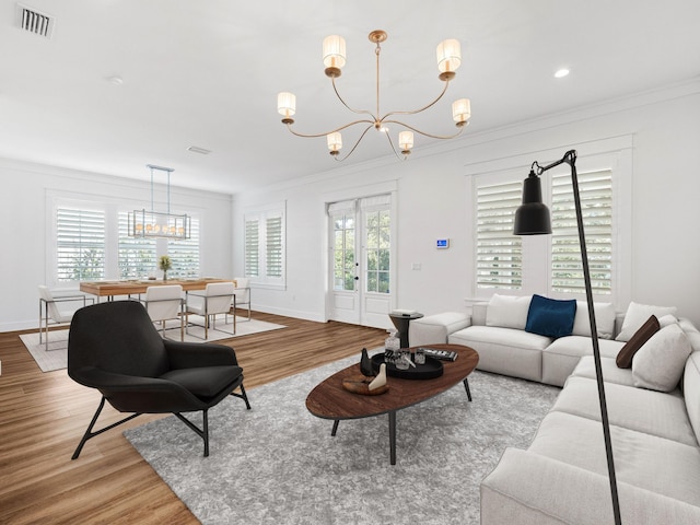 living room featuring a notable chandelier, crown molding, and light hardwood / wood-style floors