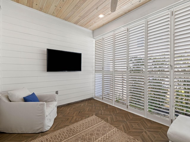 living area with wooden ceiling, dark parquet floors, and wood walls