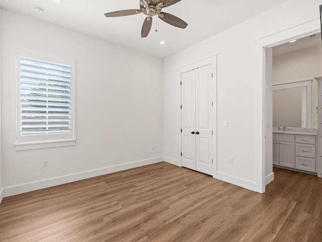 unfurnished bedroom with a closet, ceiling fan, sink, and light hardwood / wood-style flooring