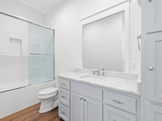 full bathroom with hardwood / wood-style flooring, vanity, toilet, and shower / bath combination with glass door