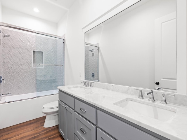 full bathroom with vanity, hardwood / wood-style floors, toilet, and combined bath / shower with glass door