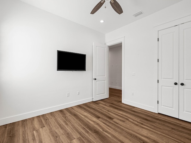 unfurnished bedroom featuring dark hardwood / wood-style flooring, ceiling fan, and a closet