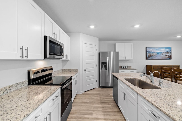 kitchen with sink, light stone counters, white cabinets, and stainless steel appliances