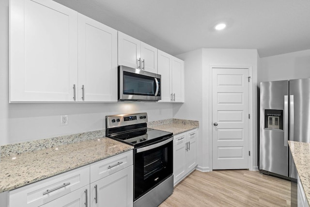 kitchen featuring white cabinetry, light hardwood / wood-style flooring, light stone countertops, and appliances with stainless steel finishes