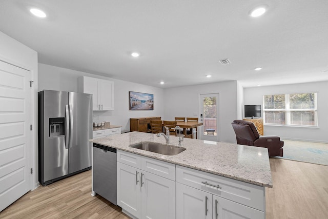 kitchen with sink, an island with sink, white cabinets, and stainless steel appliances