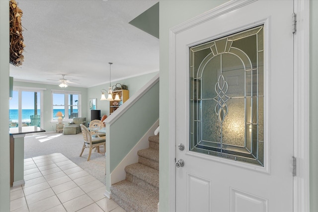 stairs featuring ornamental molding, carpet, a chandelier, and a water view