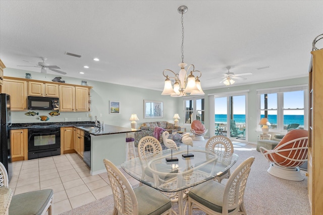 tiled dining room featuring a water view, ceiling fan with notable chandelier, sink, and a textured ceiling