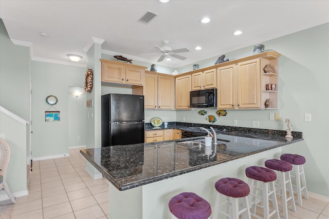 kitchen with sink, dark stone countertops, ornamental molding, black appliances, and kitchen peninsula