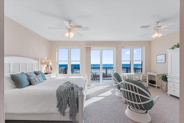 bedroom featuring a water view, light colored carpet, access to exterior, and ceiling fan