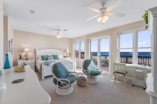 bedroom featuring access to exterior, a textured ceiling, ceiling fan, and a water view