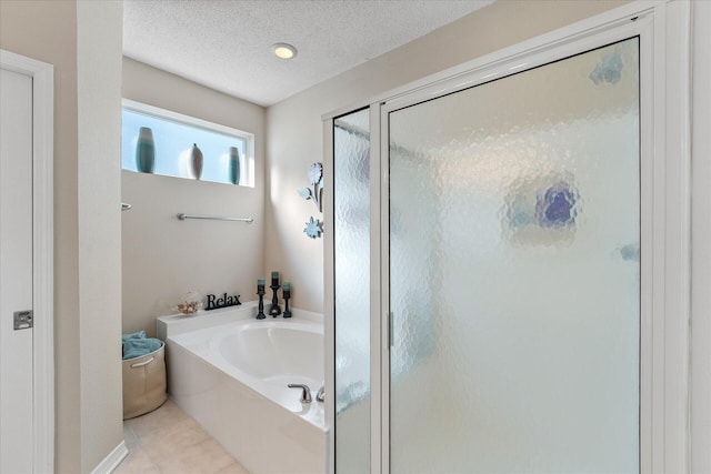 bathroom featuring plus walk in shower, tile patterned flooring, and a textured ceiling