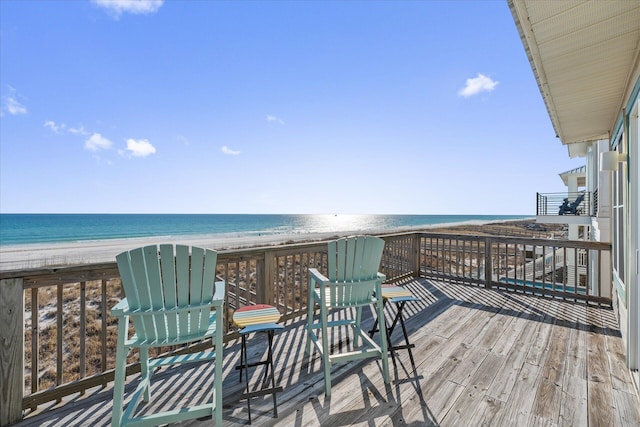 wooden deck featuring a water view and a beach view