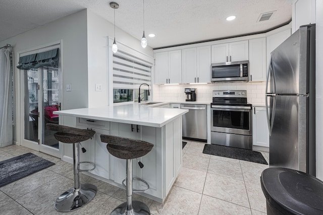 kitchen featuring pendant lighting, white cabinetry, stainless steel appliances, sink, and a kitchen breakfast bar