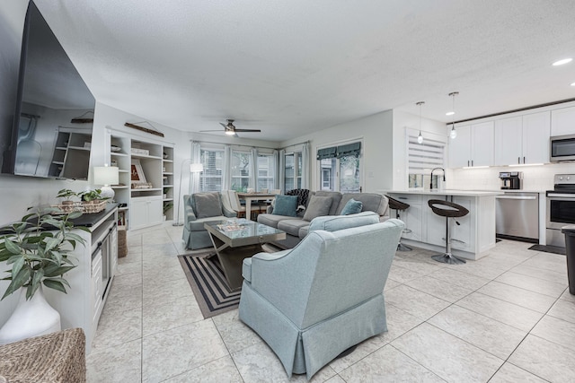 living room featuring sink, a textured ceiling, light tile patterned floors, and ceiling fan